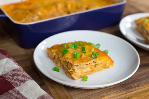Creamy Chicken Enchilada Casserole - Focus on the Plate with a Piece of the Dish Near the Blue Tray