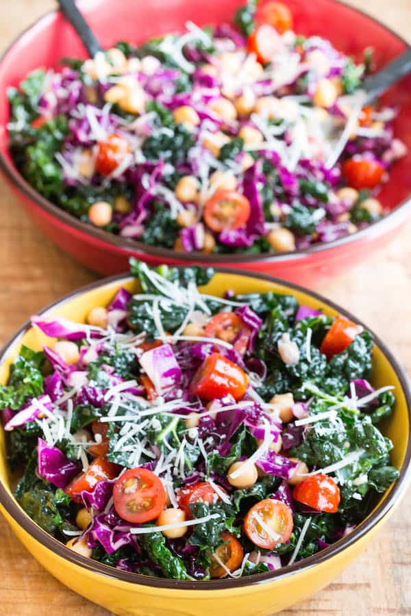 Detox Tuscan Kale Salad - Yello and Red Bowls Standing on the Table with Two Spoons in a Red One