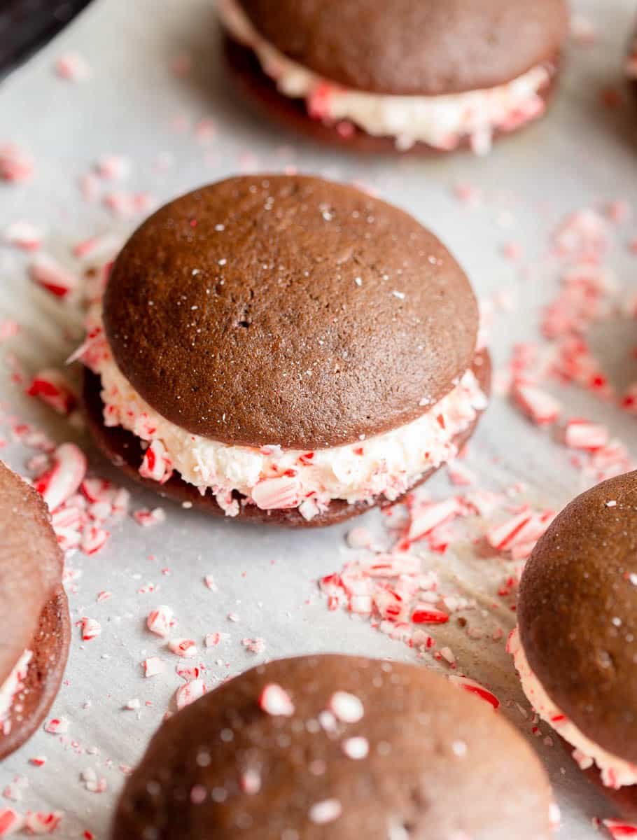 Peppermint Whoopie Pies on a baking sheet lined with parchment paper with crushed candy canes laying around them.