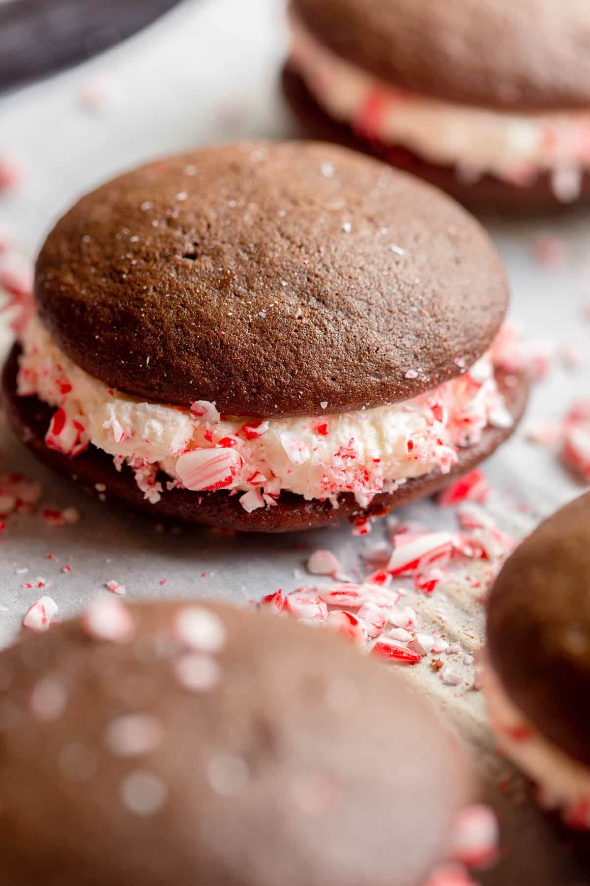 Peppermint Whoopie Pies on a baking sheet lined with parchment paper with crushed candy canes laying around them.