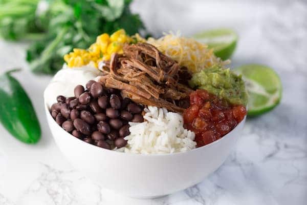 Slow Cooker Barbacoa Beef Burrito Bowls - Served in a White Bowl with Lime at the Side
