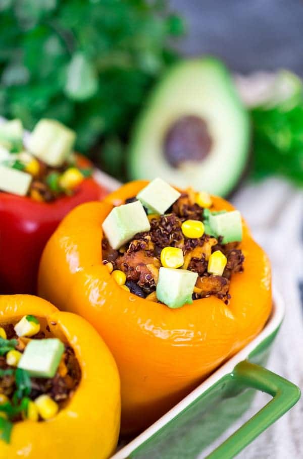 Mexican Chicken and Quinoa Stuffed Peppers with Avocado Pieces in the Background