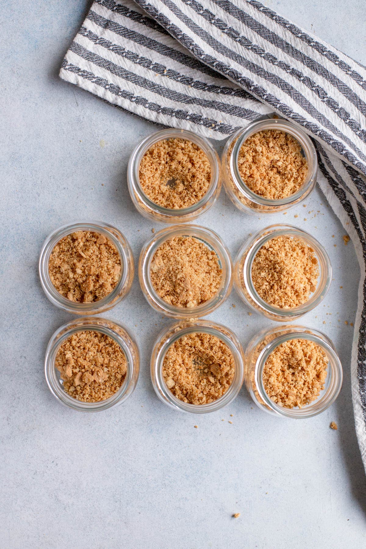 8 mini mason jars with graham cracker crumbs in the bottom of them