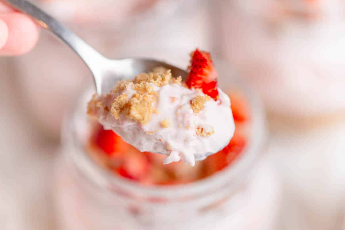 A silver spoon with a scoop of Strawberry Cheesecake Cups on it.