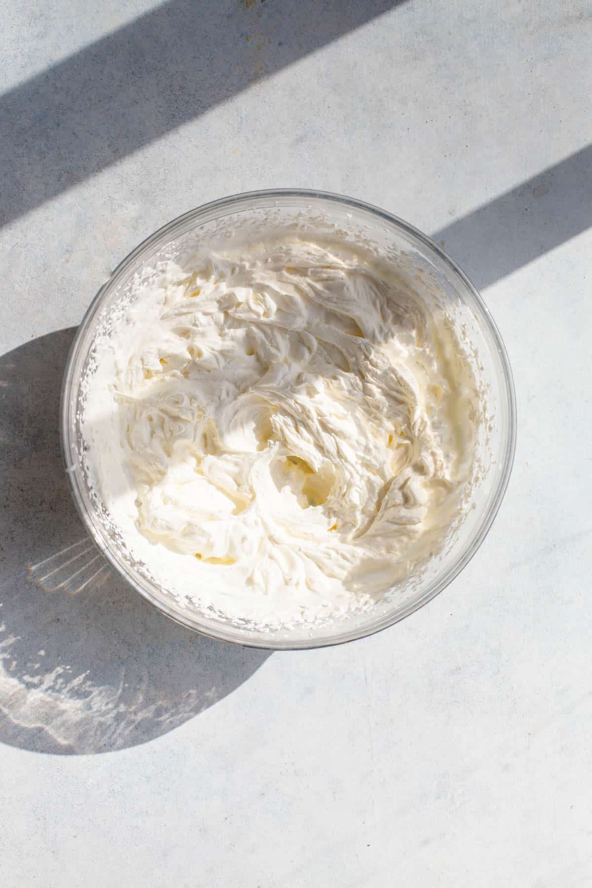 Heavy cream in a glass bowl that has been whipped until stiff peaks form.