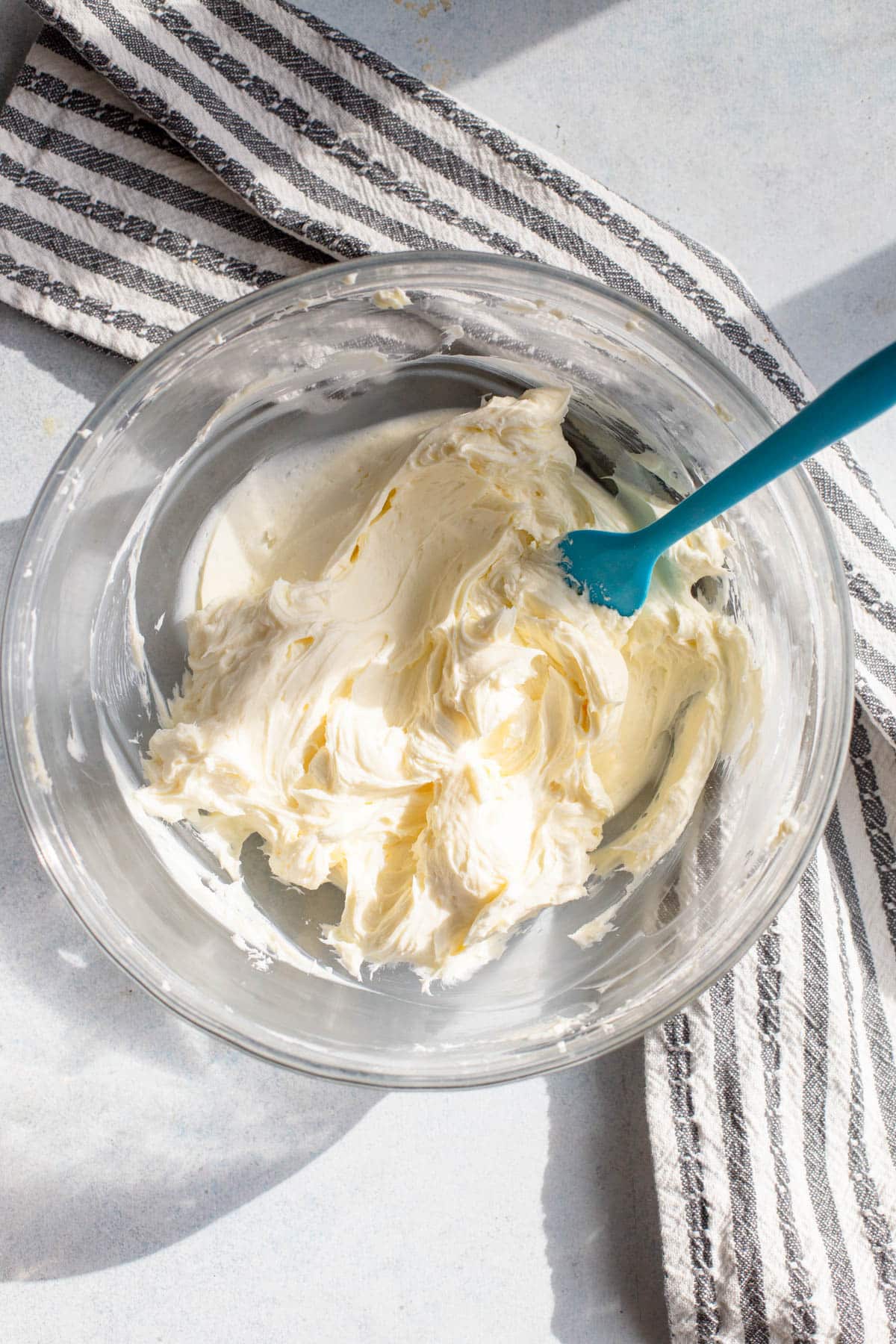 Cream cheese in a glass bowl, mixed with powdered sugar.