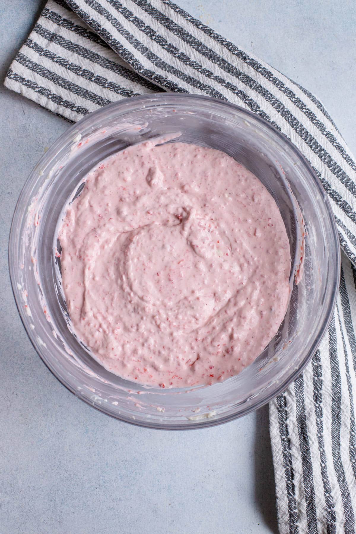 Strawberry puree that has been mixed together with the cream cheese mixture in a glass bowl.