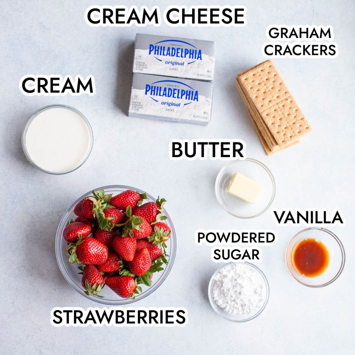 Ingredients in Strawberry Cheesecake Cups on gray background with black text labeling each ingredient.