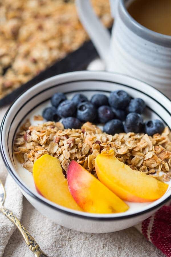 Coconut Maple Pecan Granola with a Full Cup of Drink Blurred in the Background