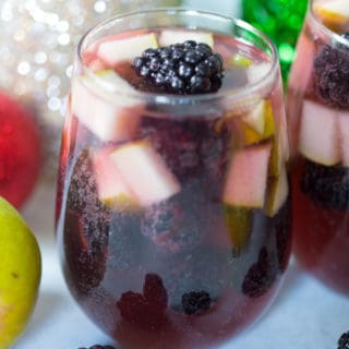 Spiced Blackberry Pear Sangria in a Glass in Focus with Festive Toys Blurred in the Background