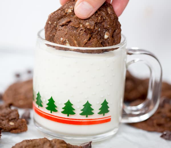 Dipping one of the Triple Chocolate Cookies into a cup with milk