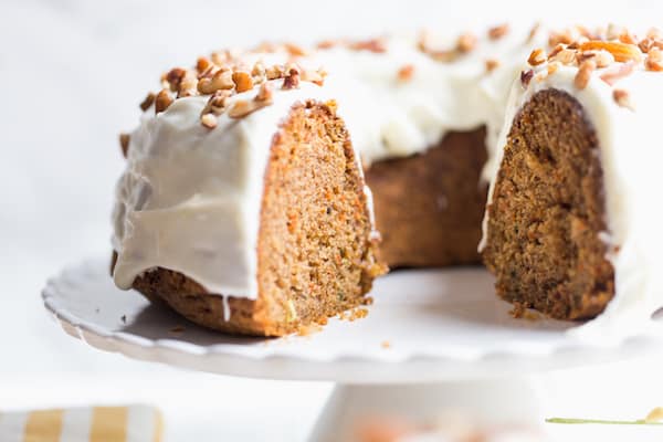 Carrot Bundt Cake with Cream Cheese Frosting Served on a White Plate. Someone Already Started It