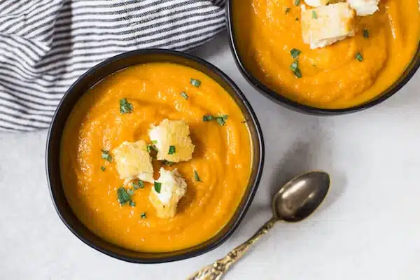 Carrot Leek Soup with Grilled Cheese Croutons Overhead on Two Bowls of Soup and a Spoon