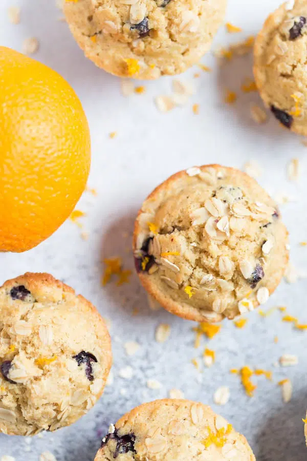 Blueberry Orange Oat Muffins with a Big Fat Orange on the Left Side of the Frame