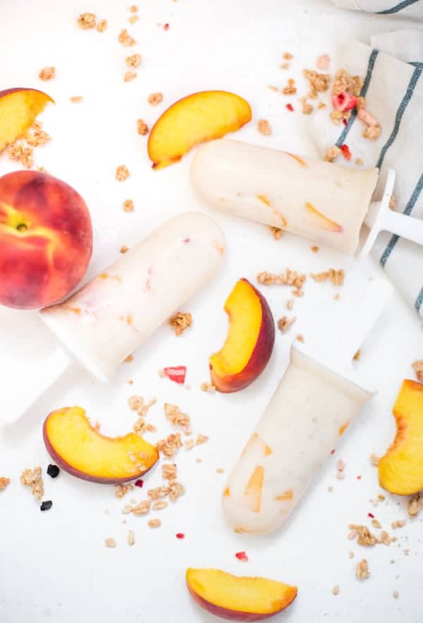 Peach Cheesecake Popsicles served with peach pieces around