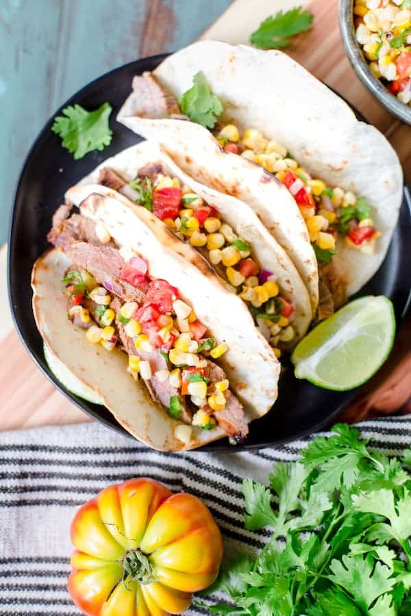 Grilled Chipotle Steak Tacos with Grilled Corn Salsa served with greens and lime