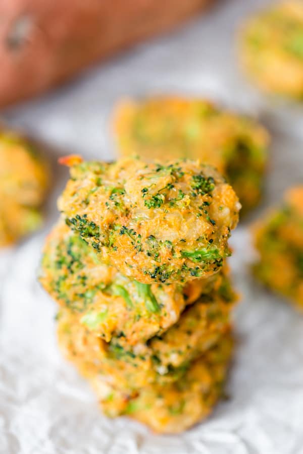 Sweet Potato Broccoli Patties stacked on top of each other with some potatoes blurred in the background
