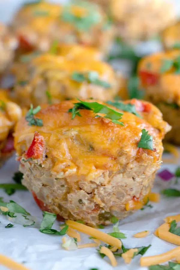 Cheesy Chicken Taco Meatloaf Muffins with Cheese and Greens Around on the Table