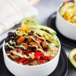 Vegetarian Quinoa Burrito Bowls with Avocado Cream Sauce in a White Bowl on a Dark Plate