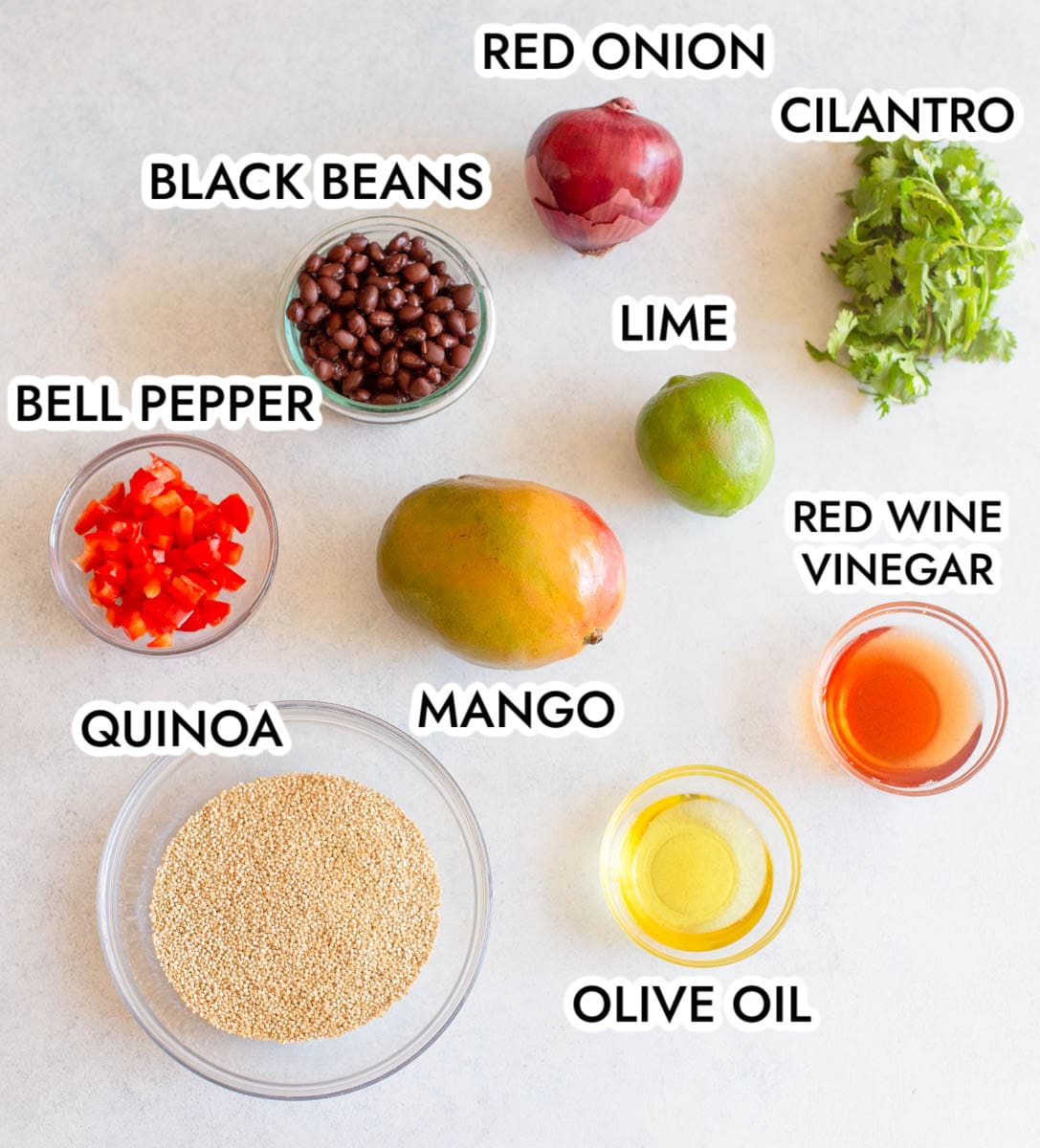 Ingredients in Mango Black Bean Quinoa Salad on a gray background labeled with black text.