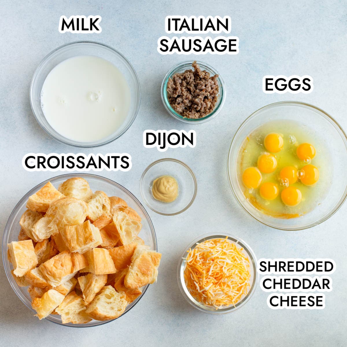 Ingredients in Sausage Croissant Breakfast Casserole with a gray background and black text.