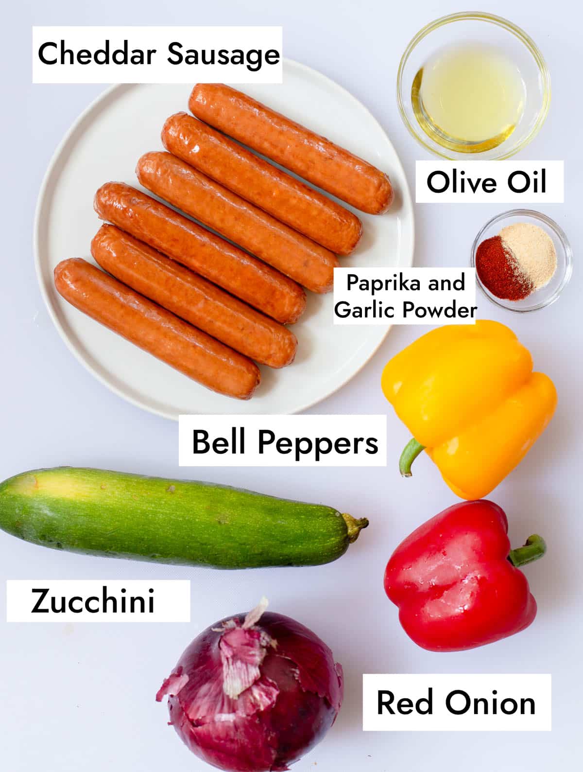 Ingredients in Grilled Cheddar Sausages including cheddar sausage, olive oil, paprika, garlic powder, bell peppers, zucchini, and red onion.