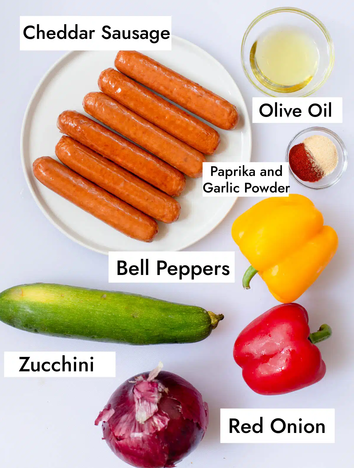 Ingredients in Grilled Cheddar Sausages including cheddar sausage, olive oil, paprika, garlic powder, bell peppers, zucchini, and red onion.