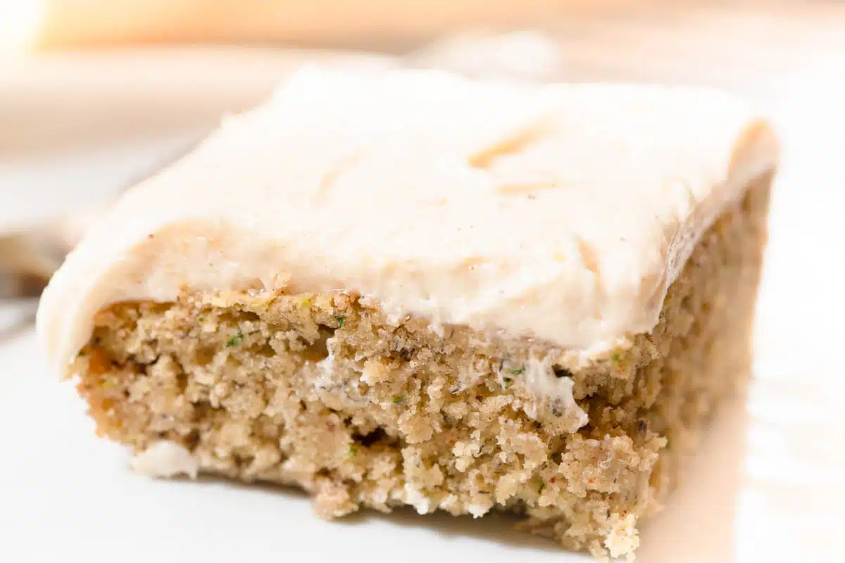 Zucchini Bars with cream cheese frosting a white plate.