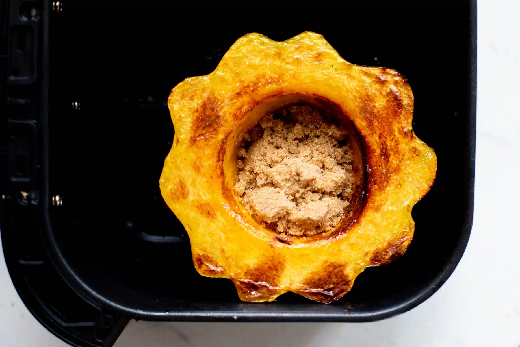Acorn squash in the air fryer with brown sugar and butter in the middle. 