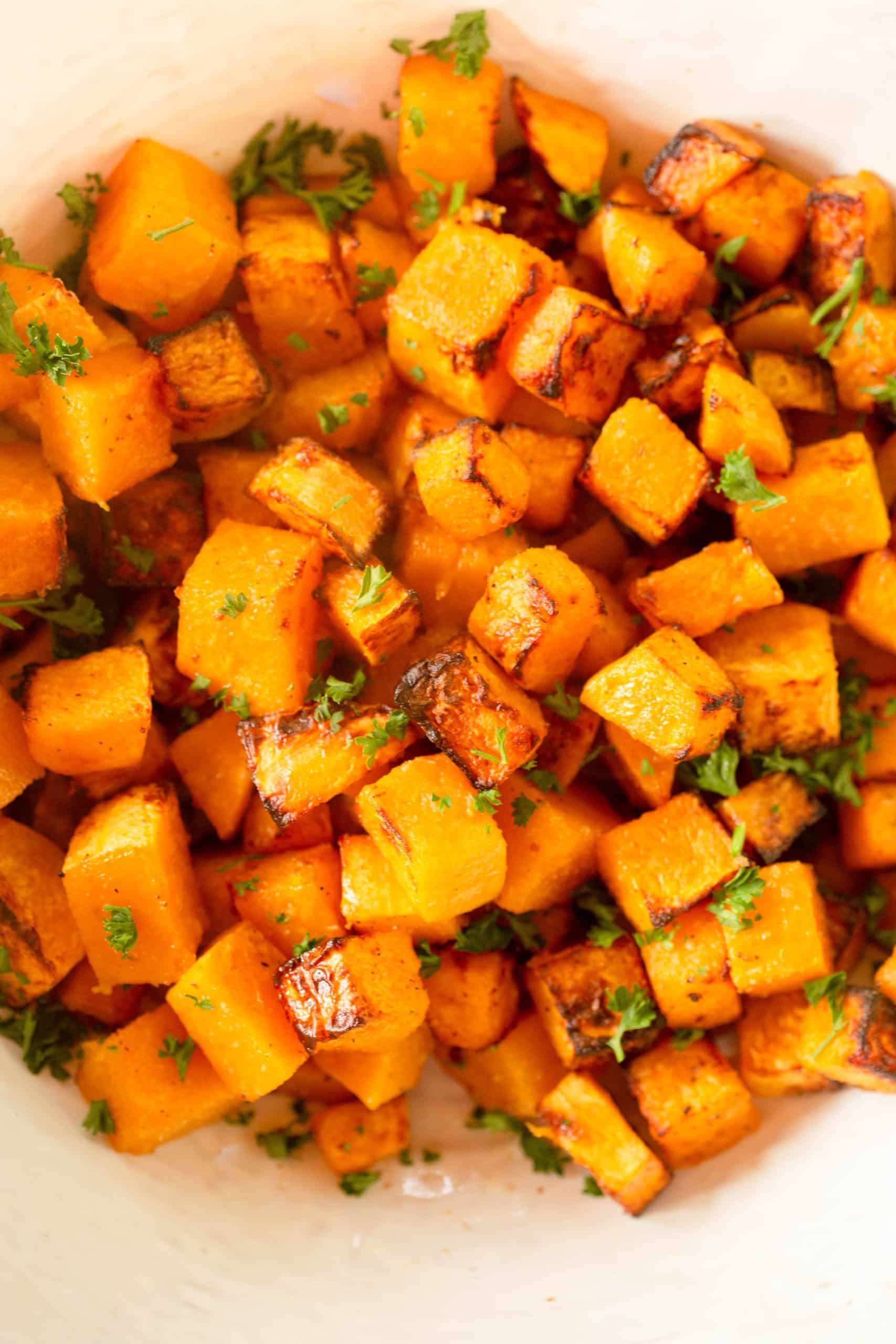 Air Fryer Butternut Squash in a bowl topped with chopped parsley. 