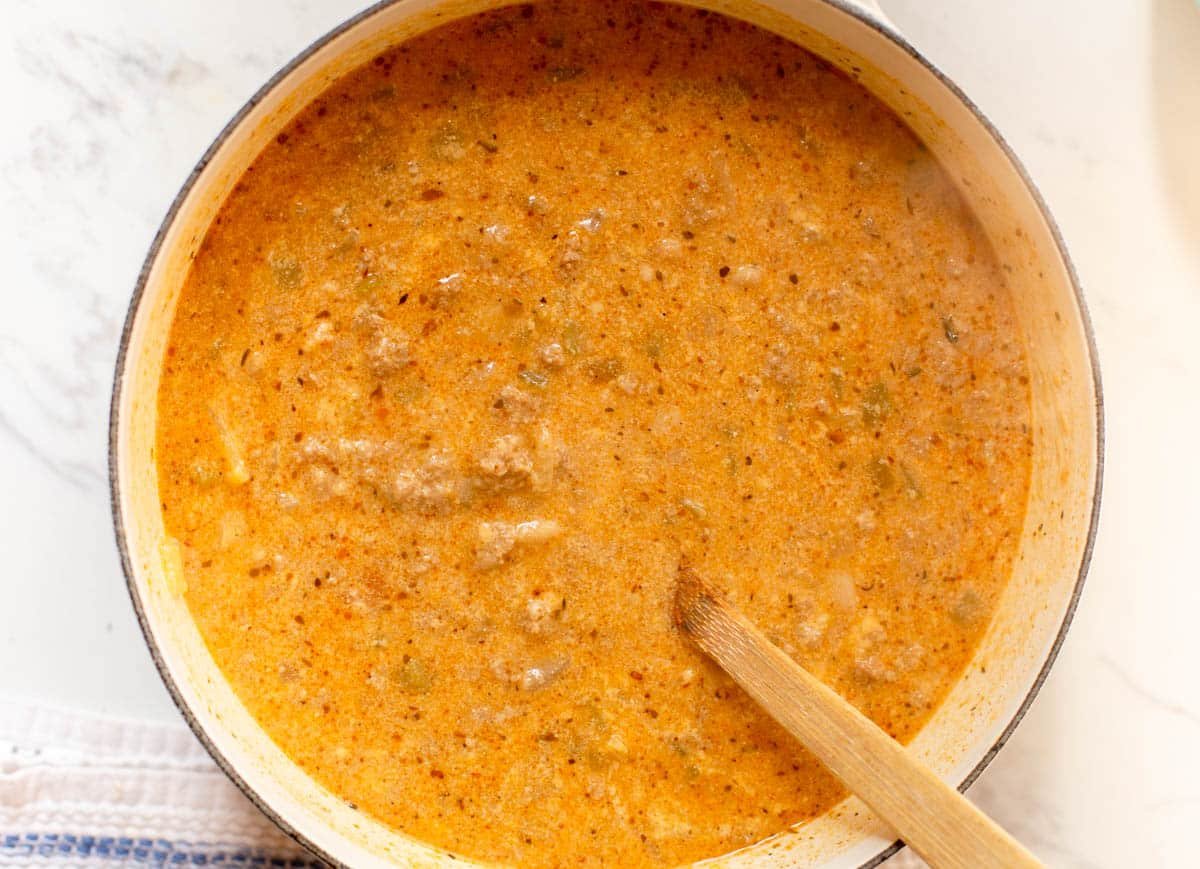 Large soup pot with white turkey chili and a wooden spoon in the pot.