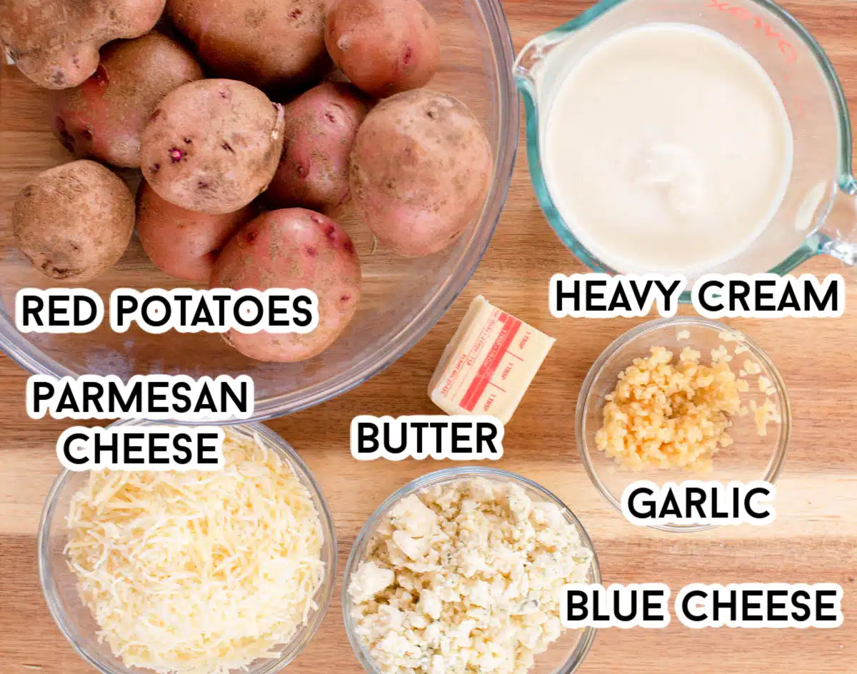 Ingredients in Blue Cheese Scalloped Potatoes including red potatoes, blue cheese, fresh minced garlic, butter, Parmesan cheese, and heavy cream.