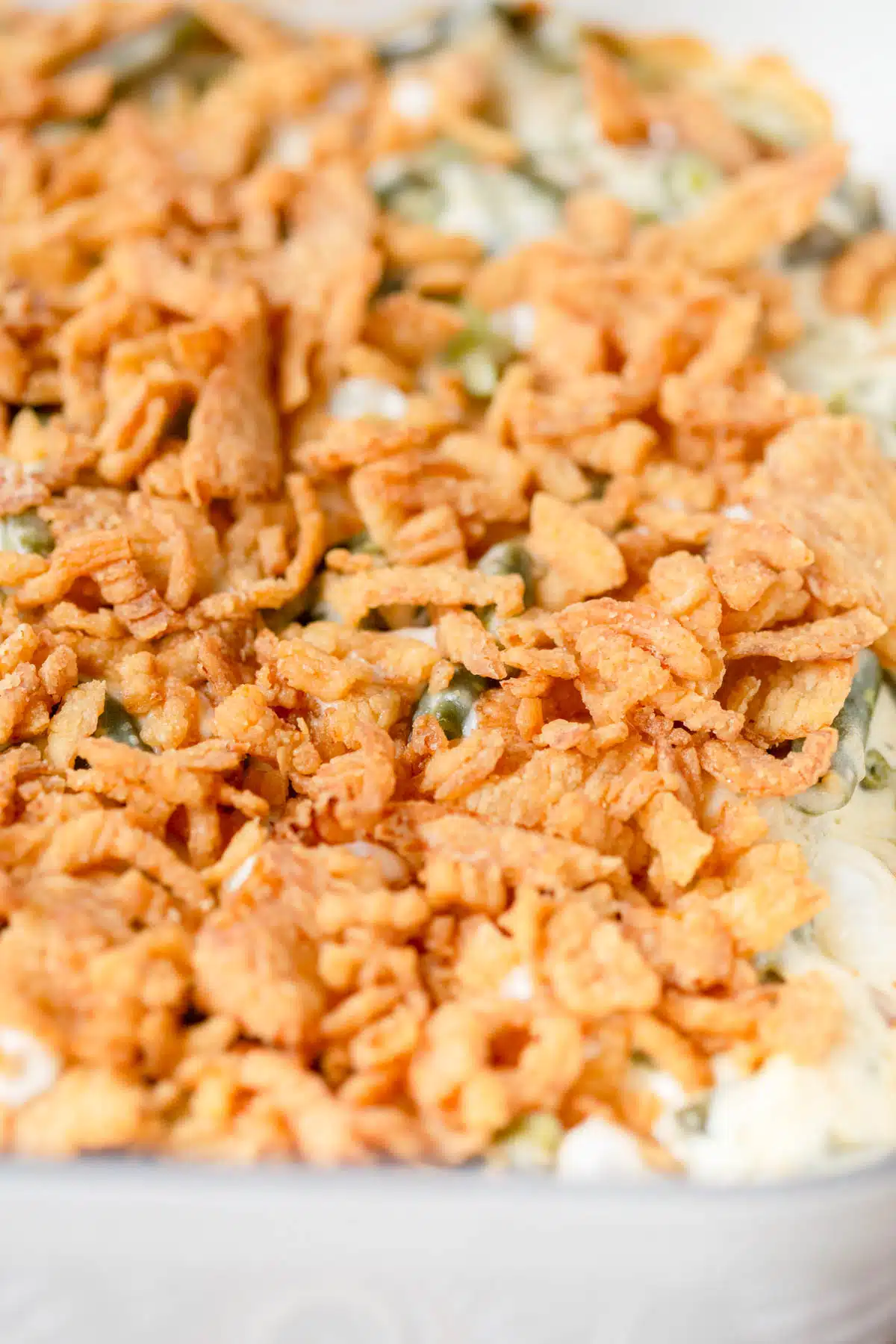 Fried onions on top of a casserole dish of cream cheese green bean casserole. 