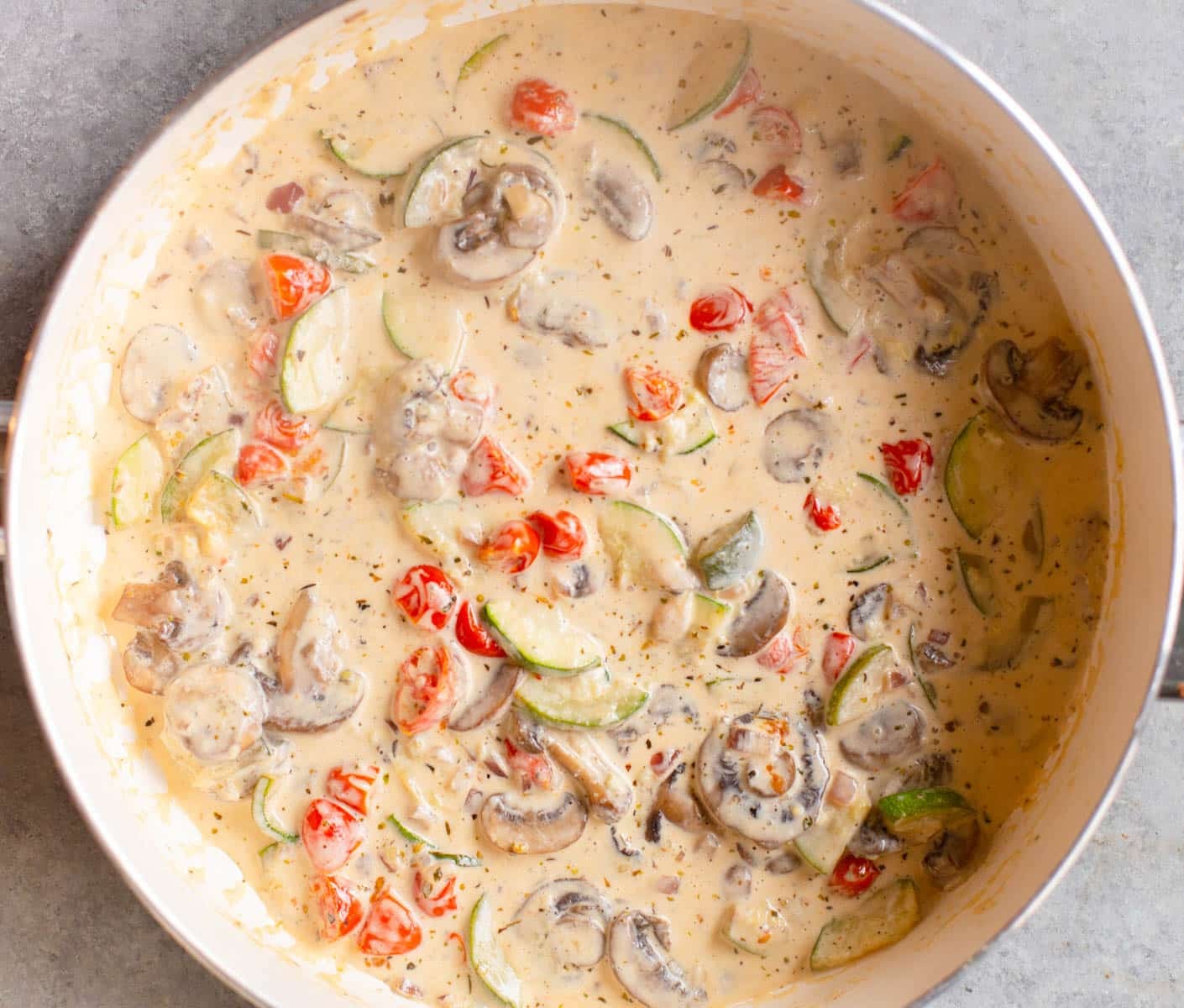 White pan with a creamy vegetable sauce in it.