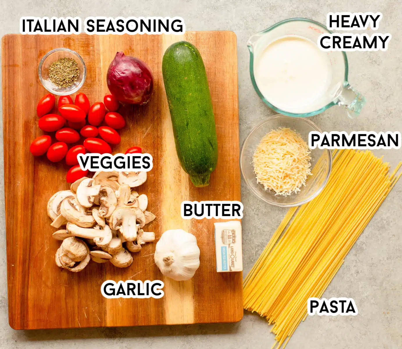 Ingredients in Creamy Vegetable Pasta including mushrooms, zucchini, onion, tomatoes, garlic, Italian seasoning, butter, Parmesan cheese, heavy creamy, and spaghetti noodles. 