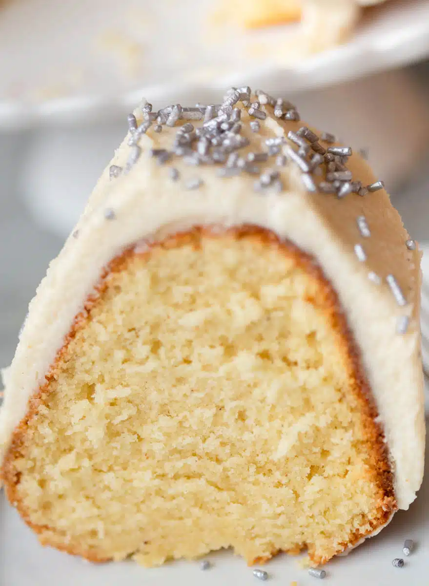Boozy Eggnog Bundt Cake on a white plate with silver sprinkles on top. 