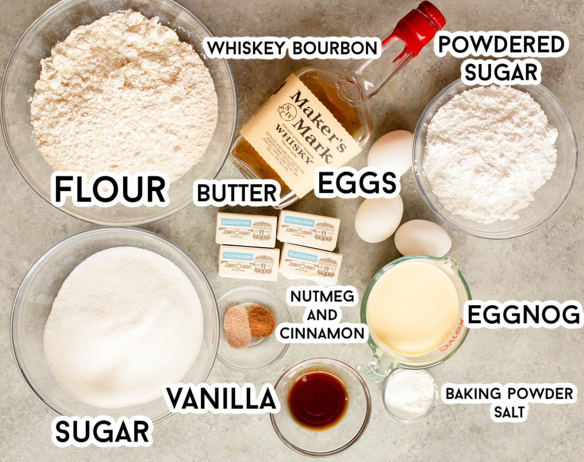 Ingredients in eggnog bundt cake - flour, sugar, vanilla, nutmeg, cinnamon, eggnog, baking powder, salt, powdered sugar, eggs, butter, and bourbon.