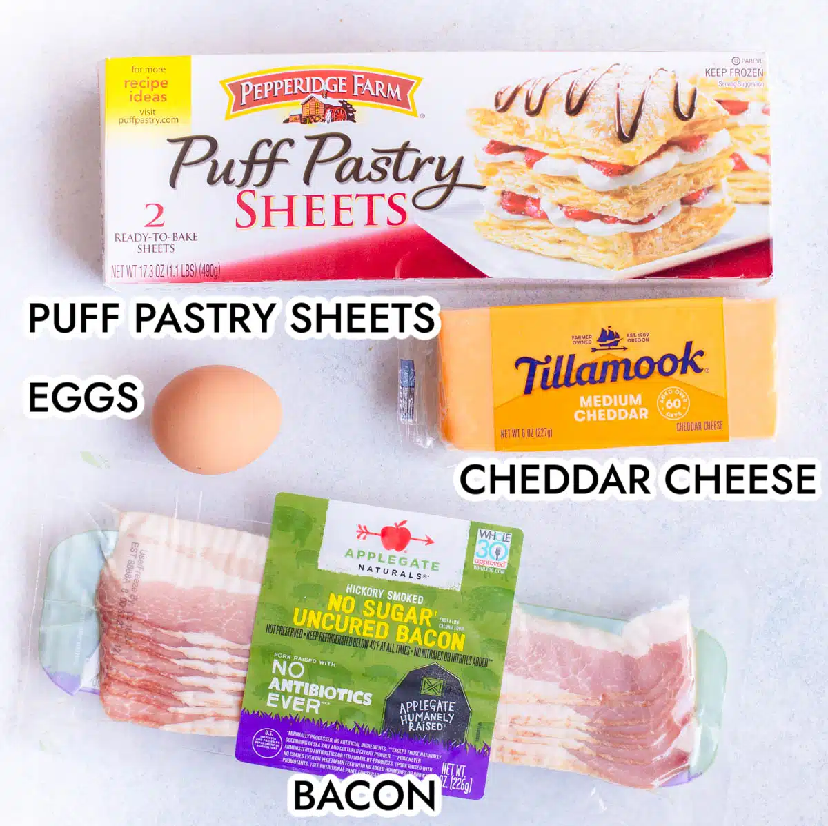 Ingredients in Bacon Cheese Turnovers including puff pastry sheets, cheddar cheese, an egg, and bacon.