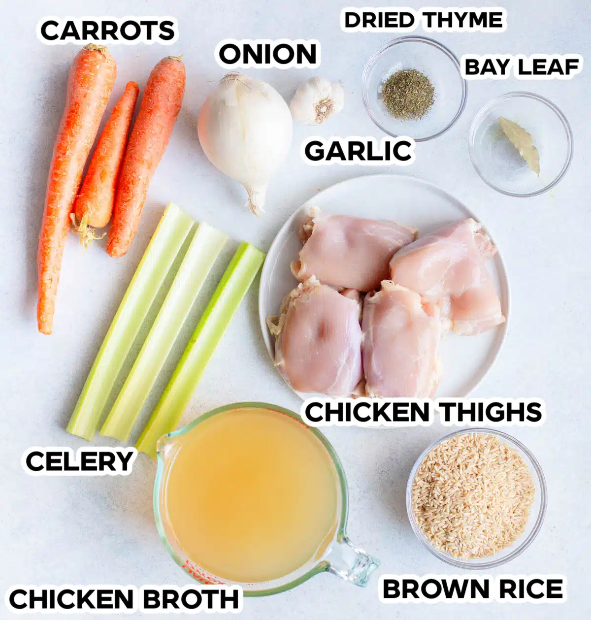 Ingredients in Chicken Rice soup including carrots, celery, onion, chicken thighs, garlic, brown rice, chicken broth, dried thyme, and a bay leaf. 