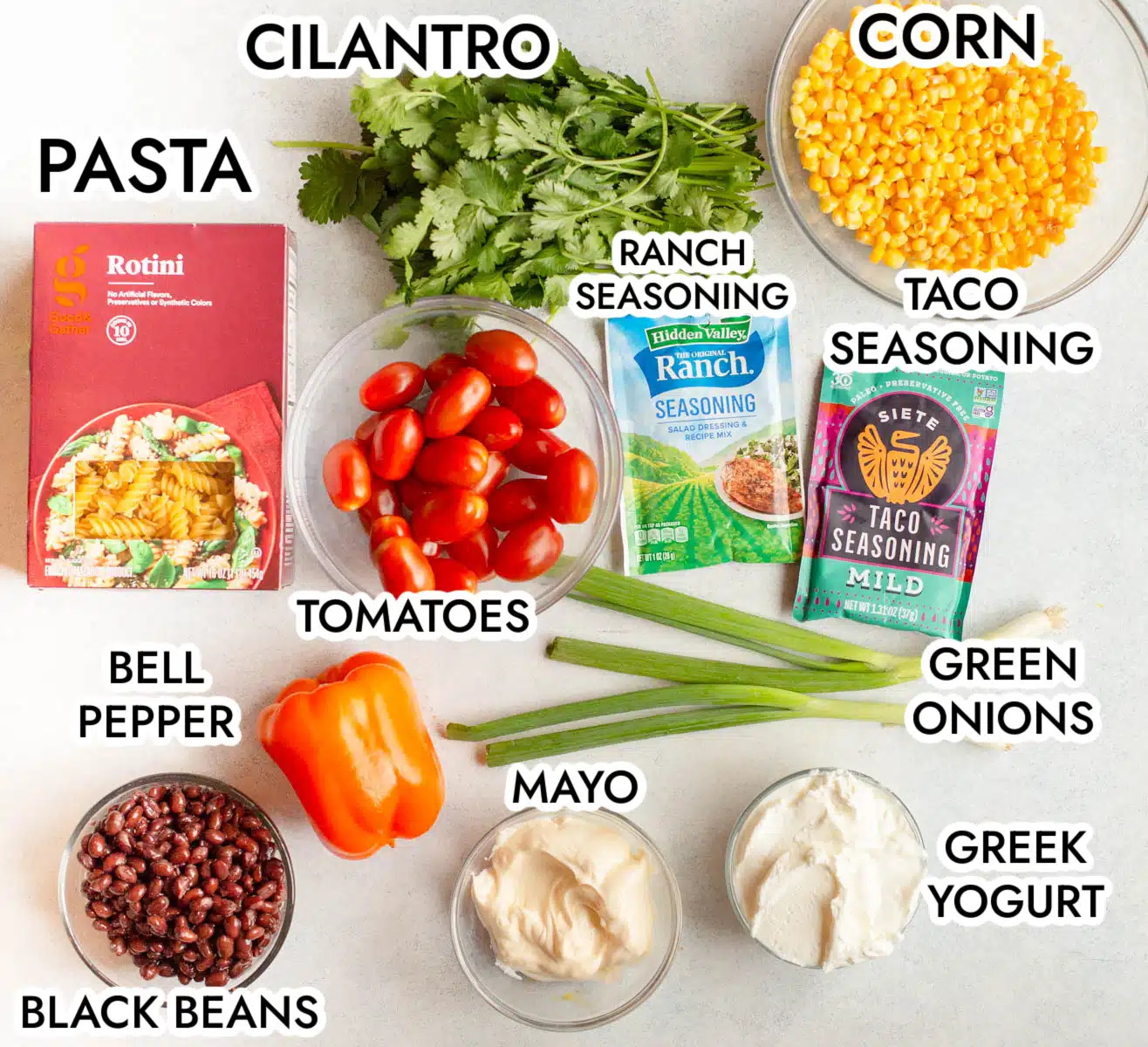 Ingredients in Southwestern Pasta Salad including rotini pasta, cilantro, corn, taco seasoning, ranch seasoning, grape tomatoes, green onions, bell pepper, black beans, mayo, and Greek yogurt. 
