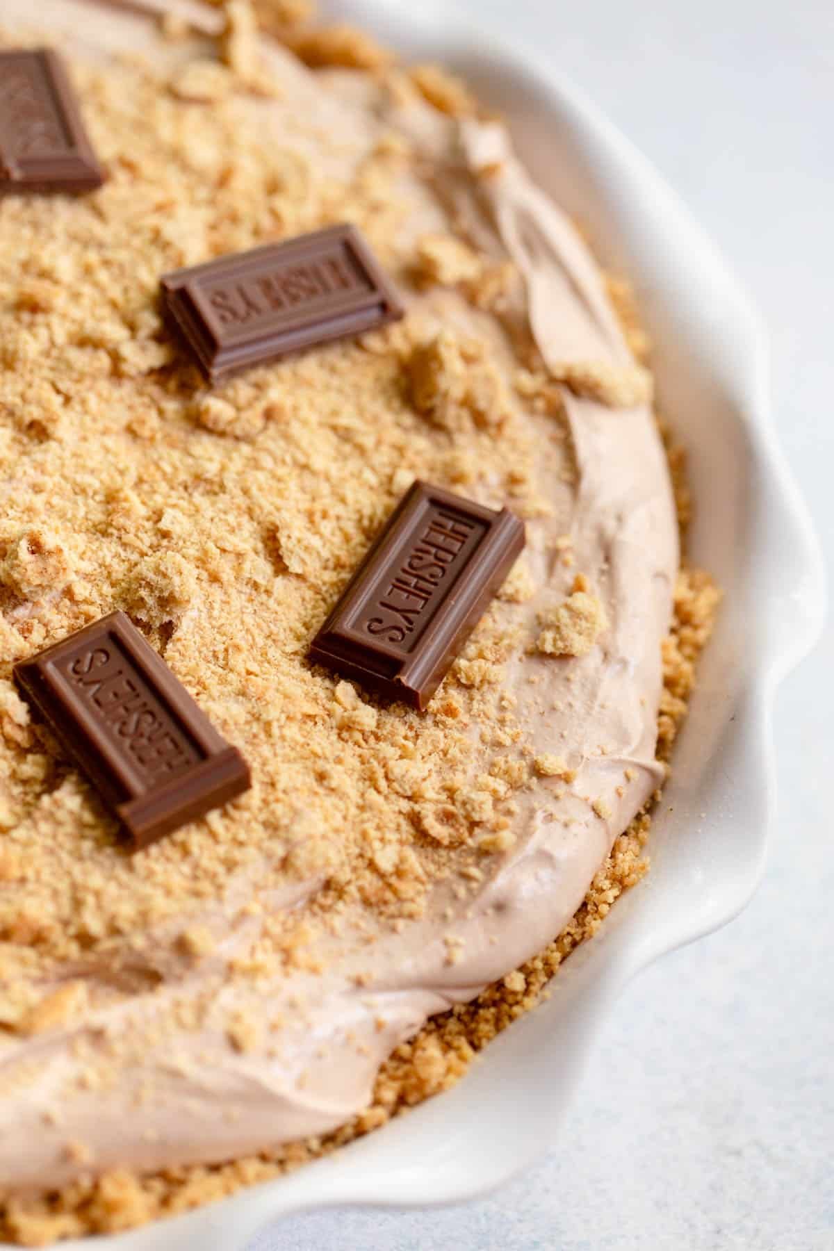 No Bake S'Mores Pie topped with graham cracker crumbs and pieces of Hershey's chocolate. 