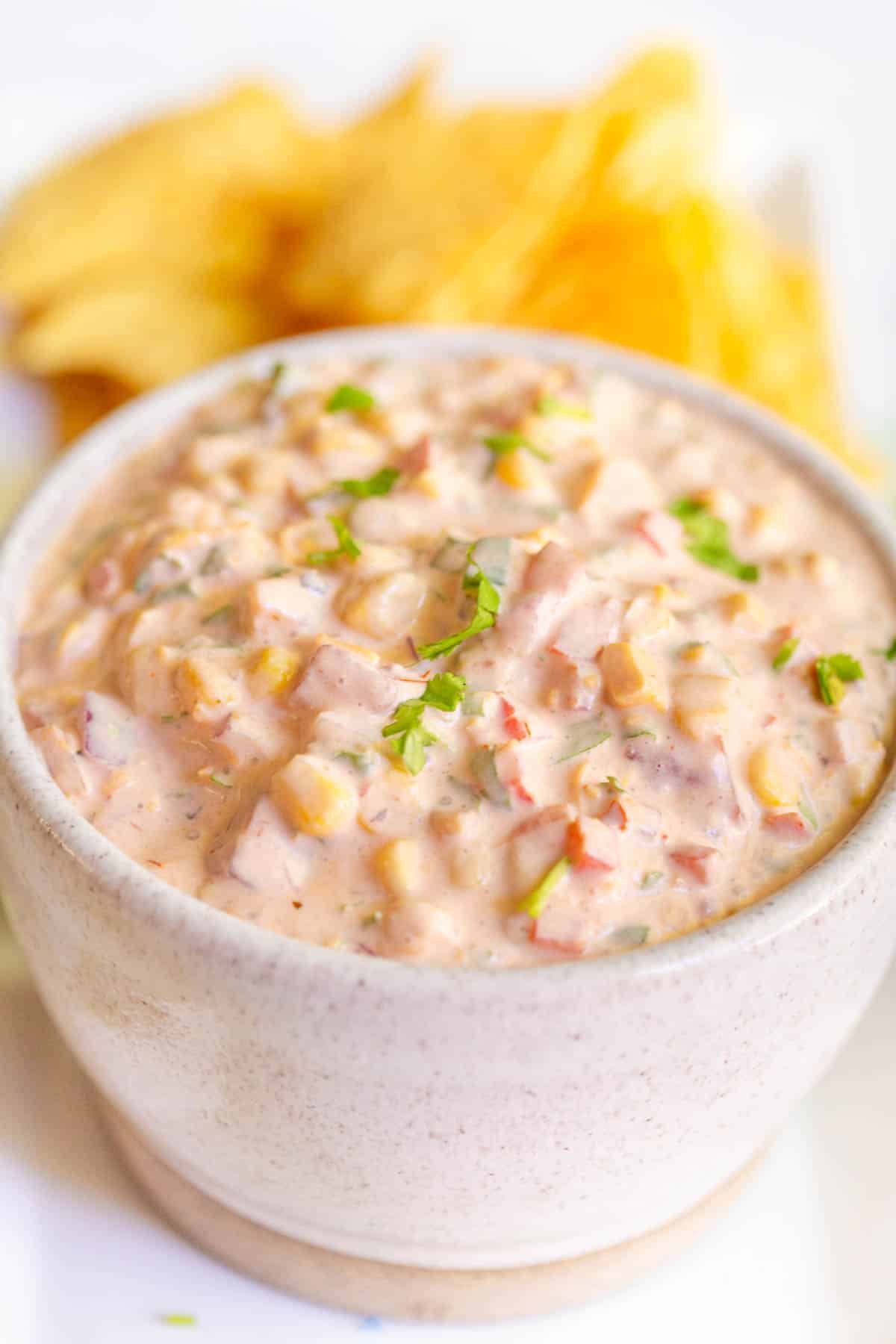 Cream Cheese Salsa Dip in a white bowl with tortilla chips in the background. 