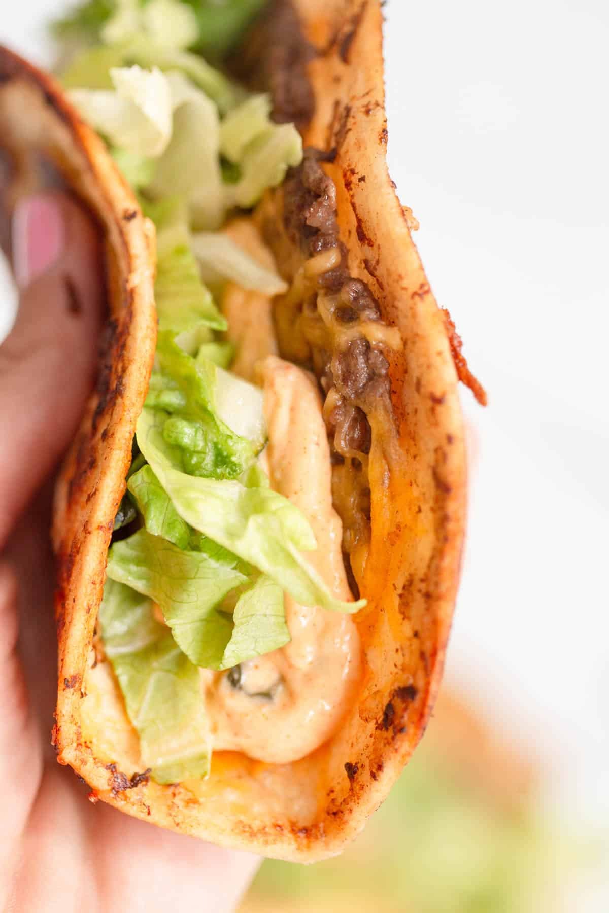A hand holding a Smash Burger Taco. 