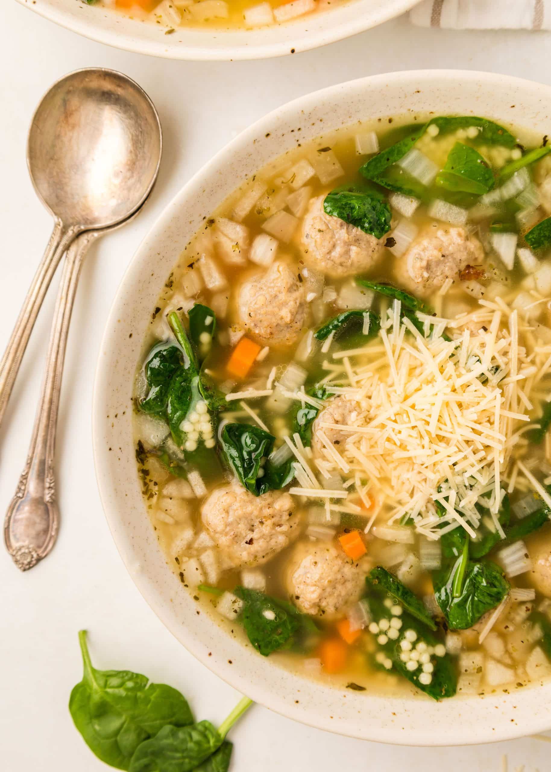 Slow Cooker Italian Wedding Soup in a speckled cream bowl with an antique spoon next to it. 