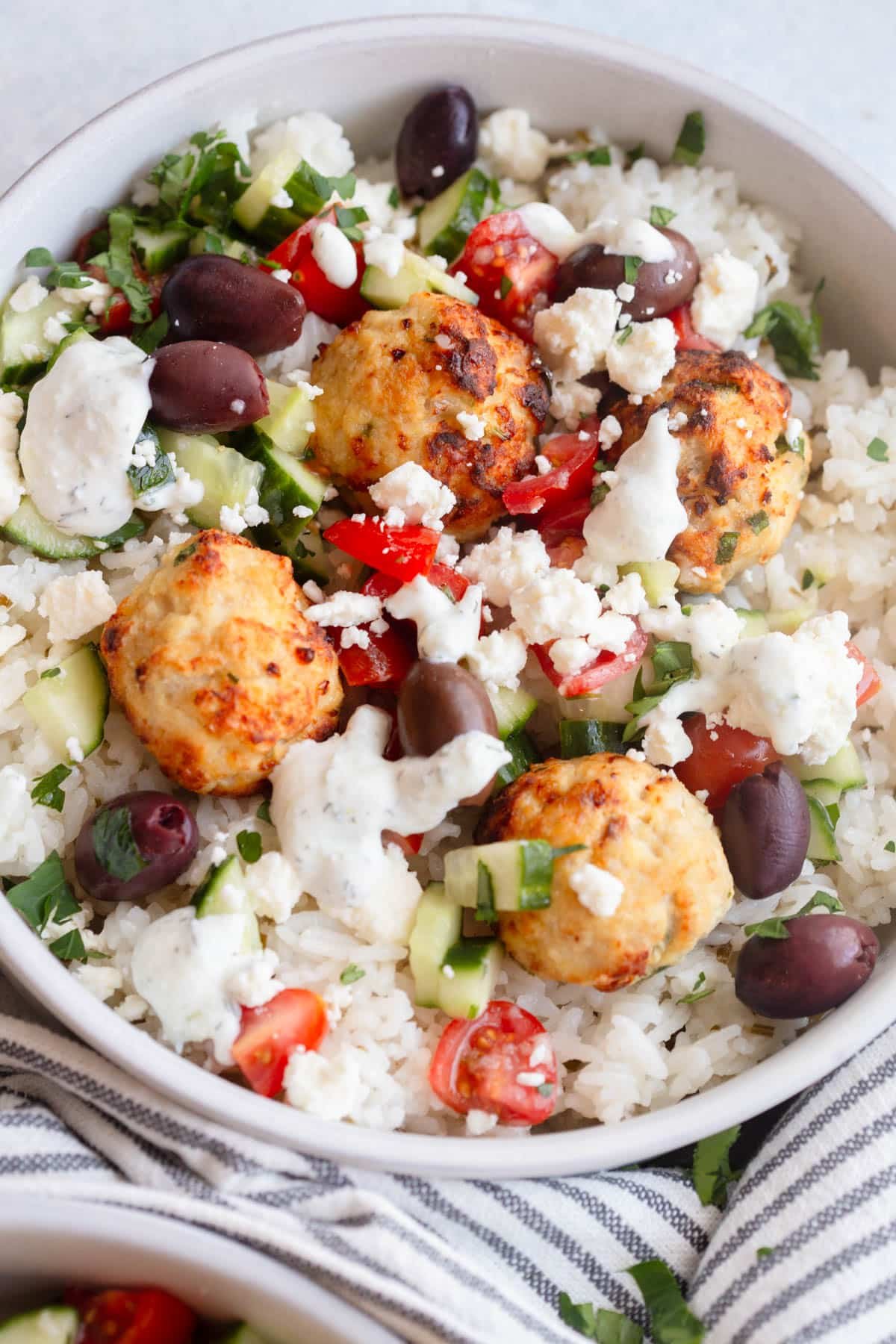 Greek Chicken Meatball Bowls in a shallow cream colored bowl .