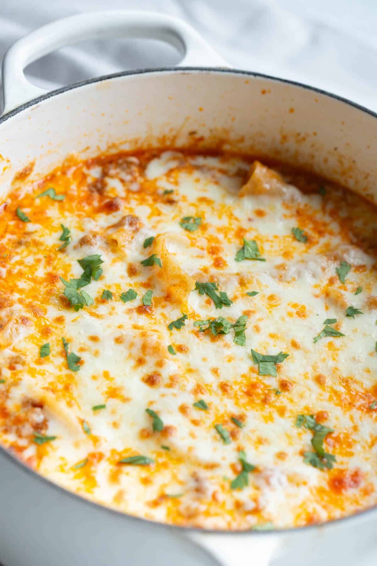 High Protein Lasagna in a Dutch oven with chopped parsley on top. 