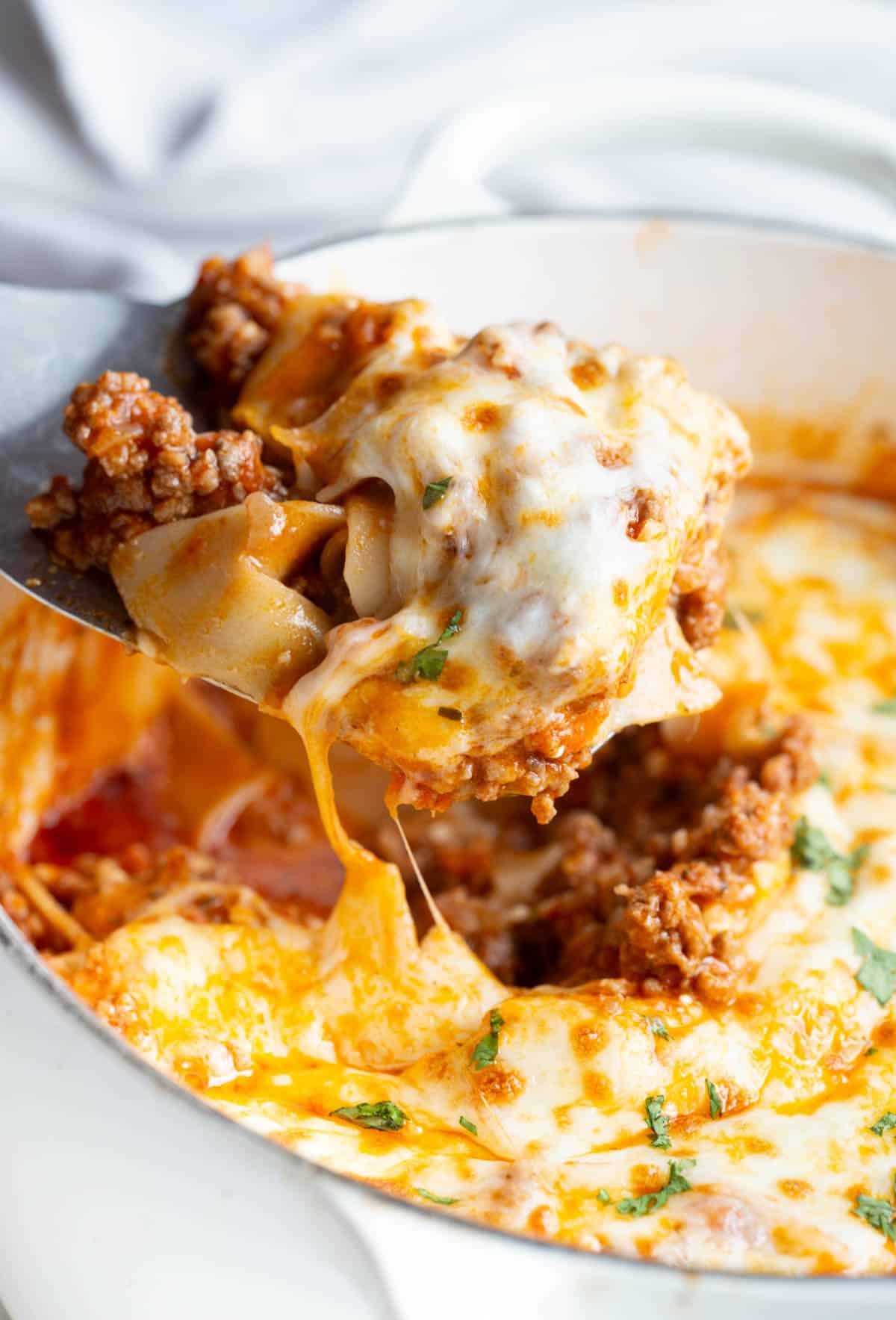 A dutch oven of high protein lasagna, with a metal spatula holding a scoop of it. 