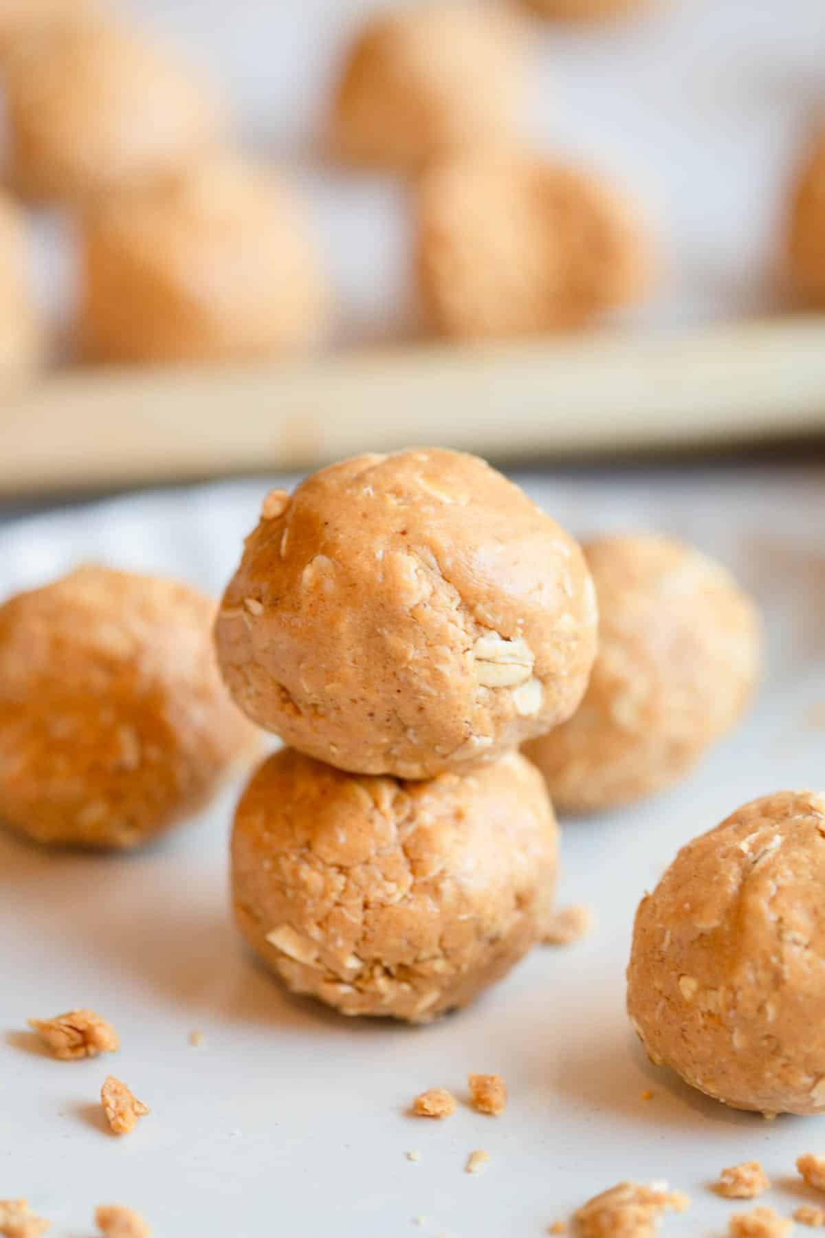 Oatmeal Protein Peanut Butter Balls on a plate, stacked on top of each other, with other balls in the background. 