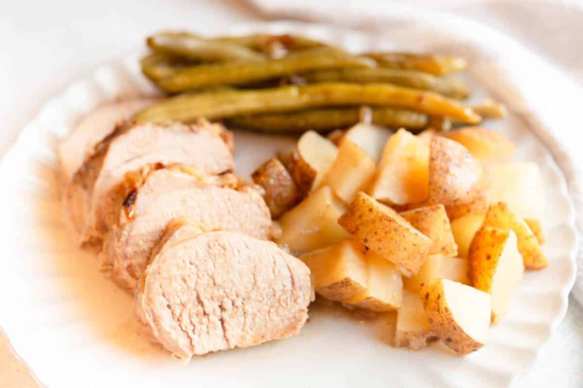 Slow Cooker Pork Tenderloin and Potatoes on a cream colored scalloped plate. 