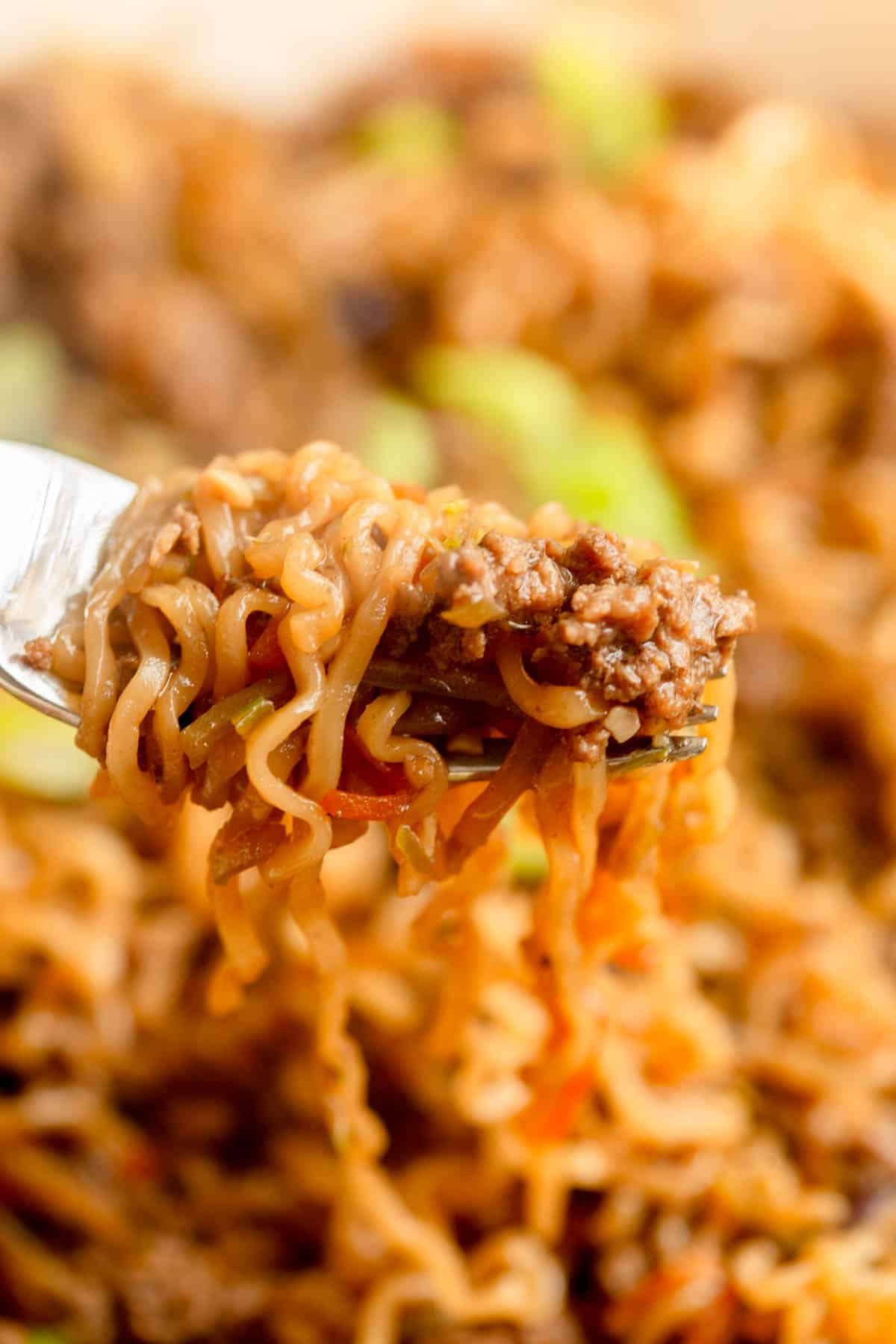 A fork with Ground Beef Ramen Noodles wrapped around it, topped with sliced green onions. 